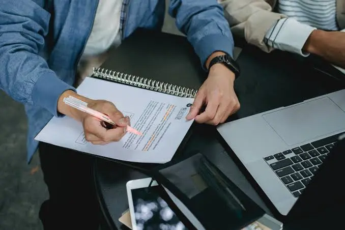 Language professional editing and checking a document beside a laptop, illustrating Request a Translation or Interpretation Quote in Uganda Language professional editing and checking a document beside a laptop, illustrating Request a Translation or Interpretation Quote in Uganda