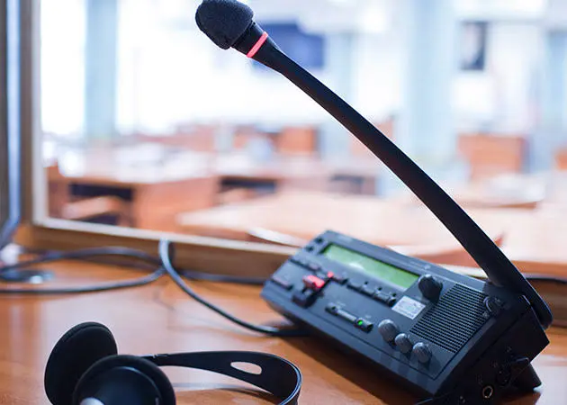 Microphone audio, channels, consoles and receivers should be tested together before live delivery. Interpretation console and headset illustrating the guide Working with local languages in research