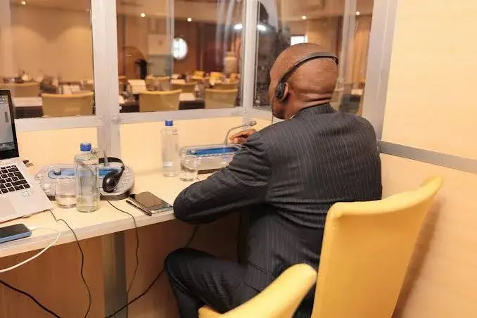 Professional interpreter working from an interpretation booth, illustrating Simultaneous Interpretation Services in Uganda Professional interpreter working from an interpretation booth, illustrating Simultaneous Interpretation Services in Uganda